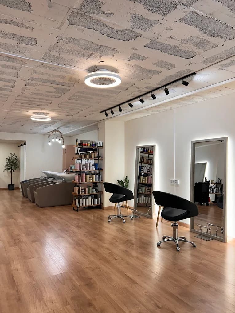 Interior de Ana Gago Hairsalon, peluquería en Carrer de Diputació 410, Eixample de Barcelona — puestos de peluquería, espejos retroiluminados y estantería de productos Nashi Argan
