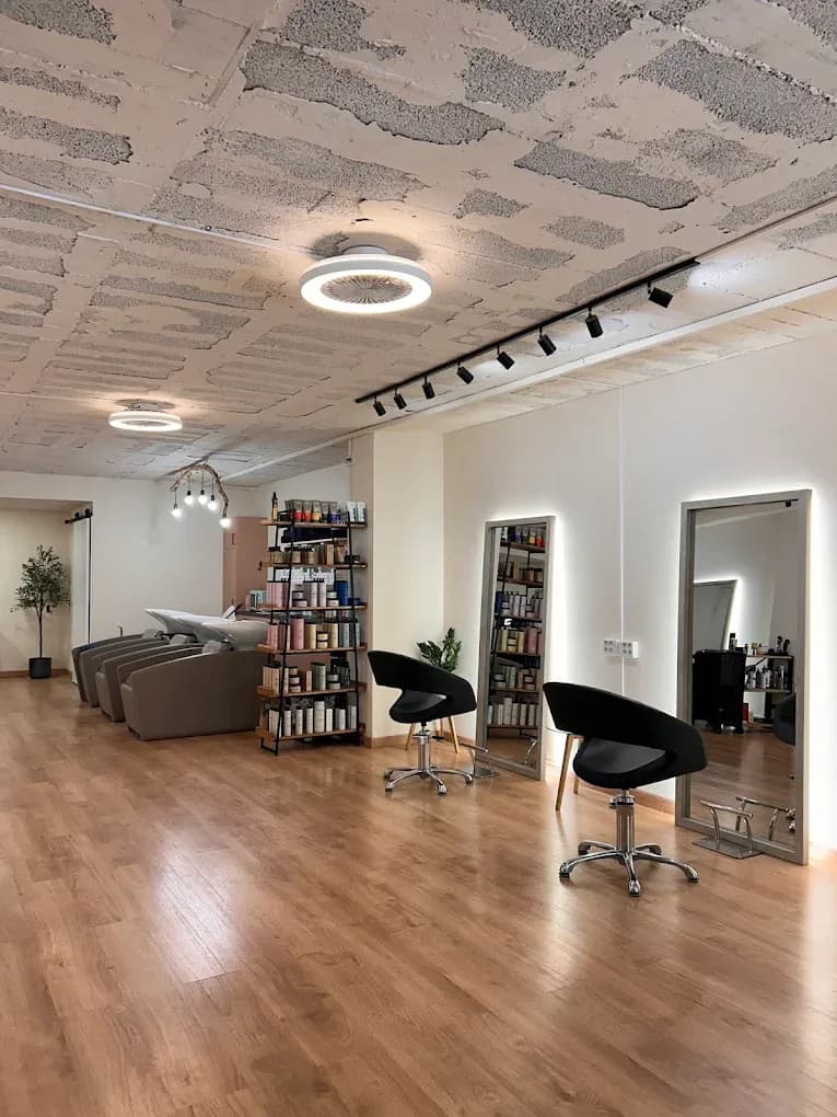 Ana Gago Hairsalon interiør, Eixample Barcelona Indre af Ana Gago Hairsalon i Eixample Barcelona — arbejdspladser, baggrundsbelyste spejle og Nashi Argan produkthylder